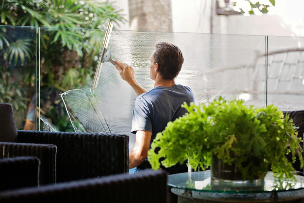 Streifenfreie Fensterreinigung mit Abzieher und Seifenwasser an einem Balkon.